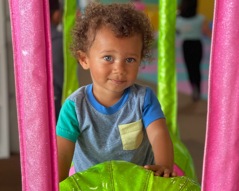 A young child plays calmly in a softly lit indoor play space — Planet of Play's Sensory-Friendly Sessions are designed for children who find typical play environments overwhelming.