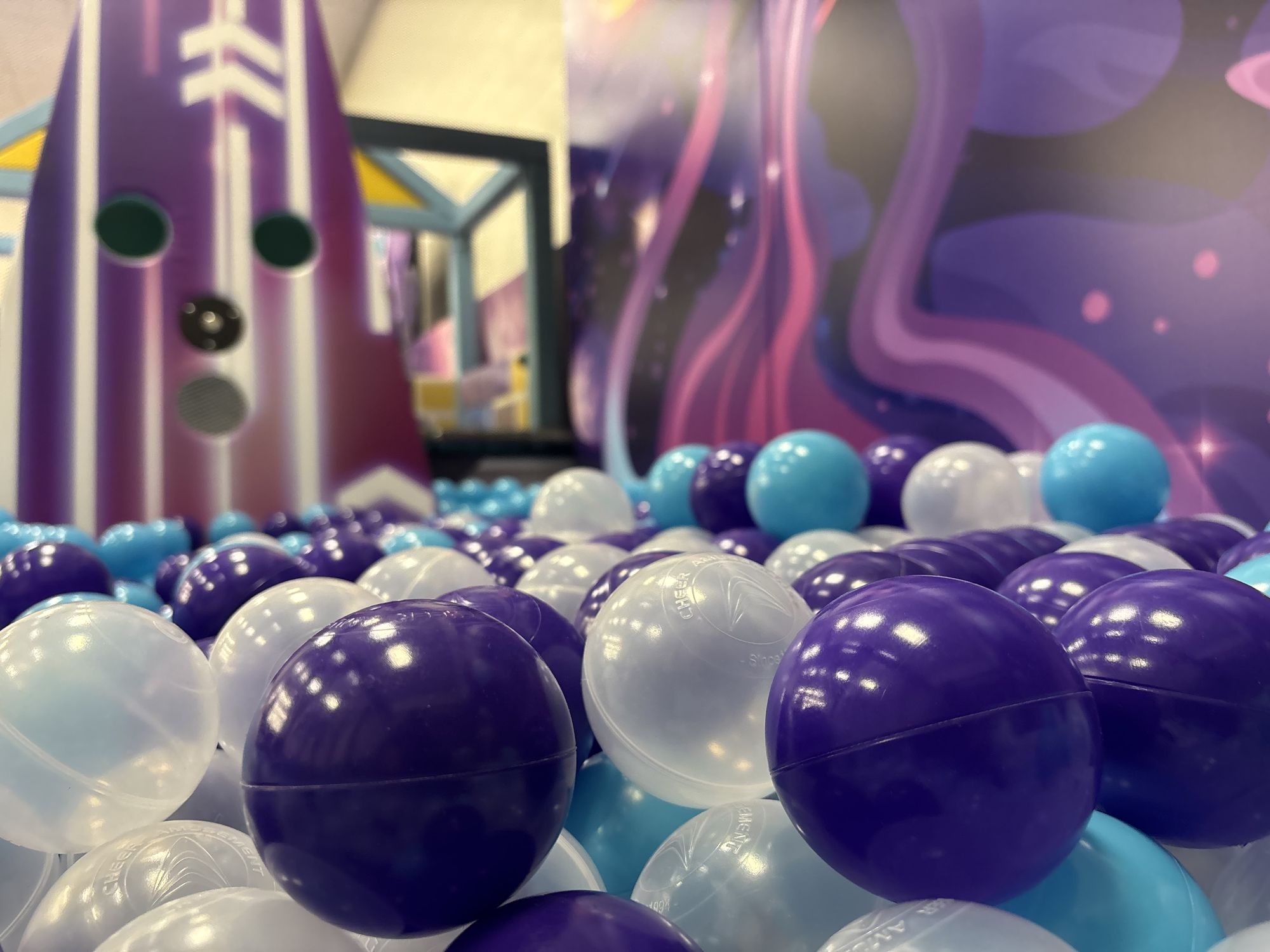 Ball pit filled with purple, white and blue balls in the toddler area
