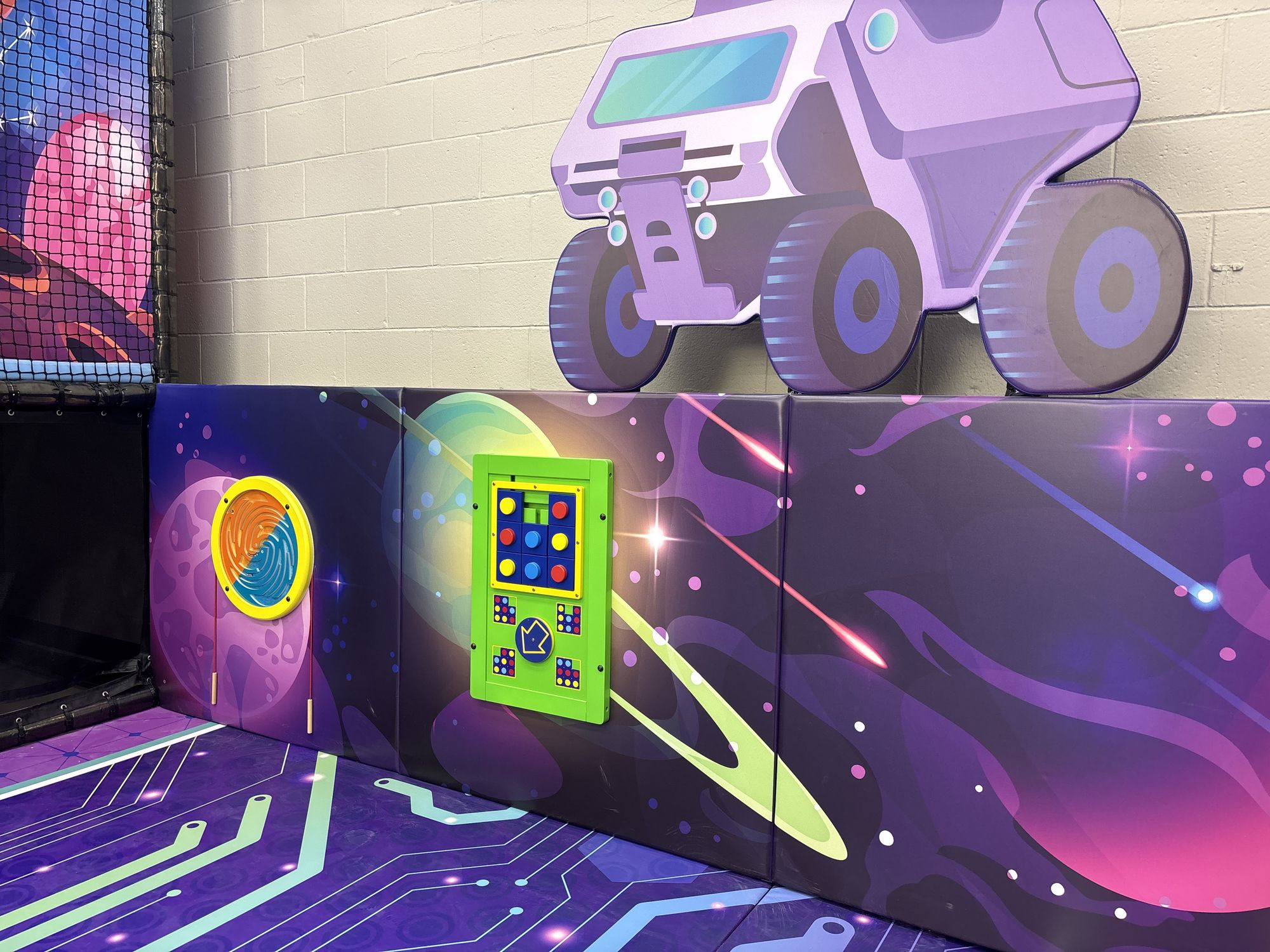 Space rover wall graphic and interactive play panel in the toddler area